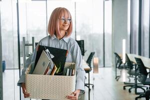 Standing ,and smiling. Unemployed ,woman with pink hair is with personal belongings after being fired photo