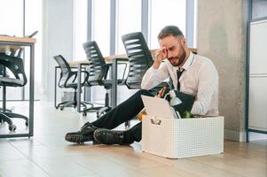 Depressed, sitting ,on, the floor.. Unemployed man is with personal belongings after being fired photo