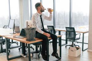 Drinking, alcohol. Unemployed man is with personal belongings after being fired photo