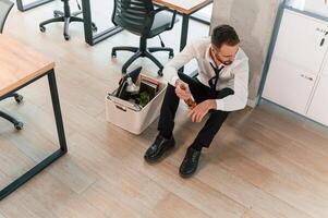 Feeling,, bad, sitting, on floor. Unemployed man is with personal belongings after being fired photo