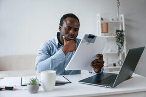 Reading information from,, document. .Businessman is working in the office by laptop photo