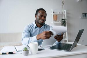 Reading information from document...Businessman is working in the office by laptop photo