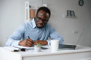 Doing, some ,paperwork. Businessman is in the office by laptop photo