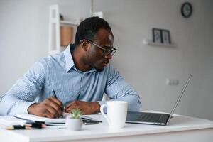 Doing ,some, paperwork. Businessman is in the office by laptop photo