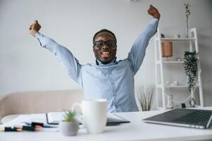 Celebrating success. With hands up.. Businessman is working in the office by laptop photo