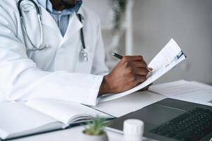 Writing information,, into the document. Black man as doctor in the clinic office photo