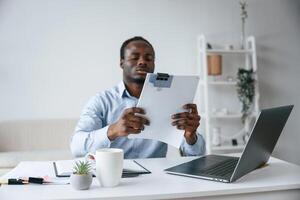 Reading information ,from, document. Businessman is working in the office by laptop photo