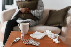 Close up view of bunch of pills on table. Sick black man is at home photo