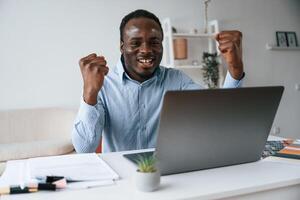 Celebrating ,success. With hands ,up. Businessman is working in the office by laptop photo