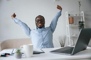 Celebrating, success. With hands up. Businessman is working in the office by laptop photo