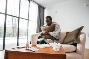 Sitting ,on sofa, holding pillow.. Sick black man is at home photo