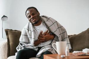 Pain in the heart area. Sick black man is at home photo