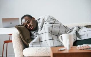 Lying down,, on the sofa. Sick black man is at home photo