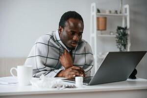 Working ,from, home, by laptop. Feeling bad. Sick black man is at home photo