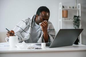 Working ,from home by laptop. Feeling bad. Sick black man is at home photo
