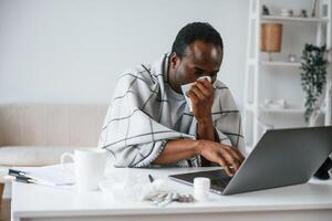 Working, from home by laptop. Feeling bad. Sick black man is at home photo