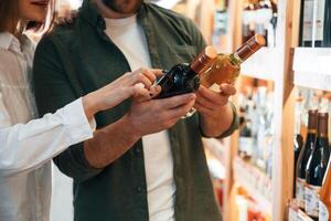 Choosing ,between, two different bottles. Man and woman in the wine shop photo
