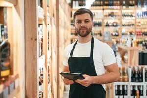 Quality control, with notepad. .Wine shop owner in white shirt and black apron photo