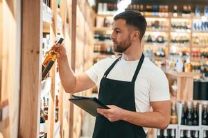 Quality ,control,, with notepad. Wine shop owner in white shirt and black apron photo
