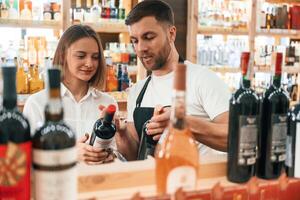 Customer,, service. The shop owner helps a young woman to choose a good wine photo