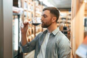 Drink,, tasting. Man is choosing wine in the store photo