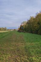 Tractor is in the middle of a field with a cloudy sky in the background photo