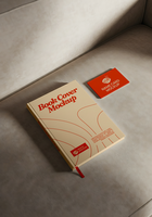 A beige book cover mockup and a red name card mockup rest on a light gray couch psd