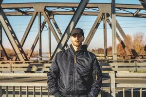 portrait of a young rapper posing on a metal bridge photo