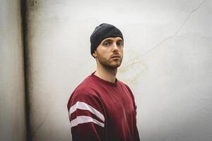 portrait of young rapper posing in front of a white wall photo