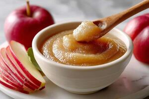 Applesauce in white bowl with fresh apples photo