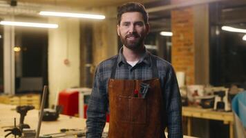 Joyful happy Caucasian worker man builder guy carpenter male looking at camera portrait indoors small business owner smiling in workshop carpentry designer work job wood master in uniform woodworking video
