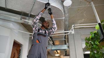 Technician installs ventilation ductwork in office ceiling video