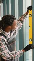African American worker installing window with level video