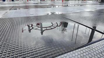 Reflection of Playground Equipment in a Water Puddle on Rubber Flooring video