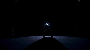 Silhouette of a dancer in move. Performer dancing on stage against spotlights on dark background. Man acting in the theater. video