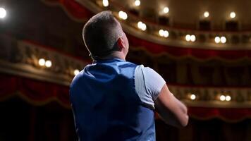 Man rehearses on stage. Actor performing from the scene gesticulating a lot on modern theater background. Rear view. video