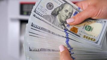 Usa money in woman's hands. Wad of one hundred dollar banknotes in hands on blur background of automatic counter machine. Finance concept. Close-up. video