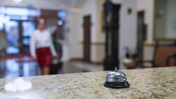 Reception lobby. Bell button on a reception table on blur background of a hotel. Lady pressing the metal bell on desk to call a receptionist in hotel. Close-up. video