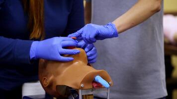 Training skills on dummy's head. Medical trainer demonstrates medical procedure to a student on a head. Practitioner learns on a doll. Close-up. video