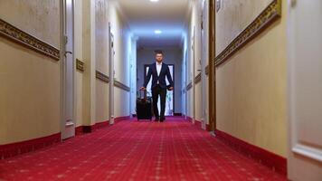 Businessman in hotel. Full-length portrait of a man with suitcase. Handsome man in elegant suit moving along the corridor of a hotel to the room. video