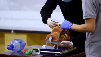 Practical skills for medical students. Instructor helps practitioner to do a medical procedure into a nose on dummy's head. video