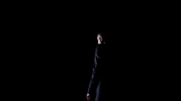 Speaker on black background. Profile view of a man talking to the audience while standing on stage. Performer in darkness. video