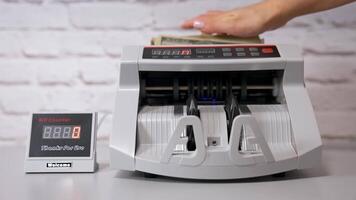 Electronic cash counting machine. Bank financial operations and calculating dollar banknotes. Female hand puts paper money into automatic equipment for counting bills. video