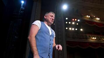 Comedian on stage. Middle-aged speaker standing on stage and talking to someone. Smiling actor rehearses on scene. video