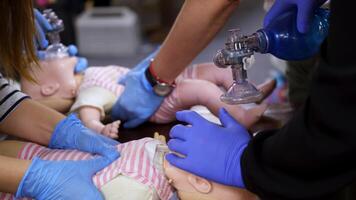 Practice of chest compression on dolls. Students teaching cardiopulmonology procedure for giving first aid on a mannequin in medical center. Close-up. video