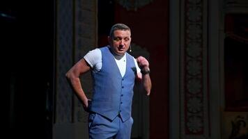 Host in grey suit on stage. Male actor starts his performance in the theater. Portrait of a comedian standing on stage and talking. video