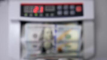 Automatic machine counting dollar banknotes. Modern banking activity. Blurred background. Hand is taking a pack of counted dollar bills from the counter machine. video