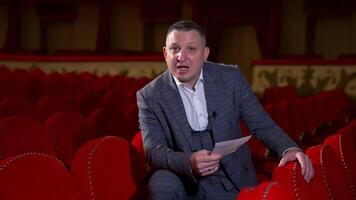 Actor at rehearsal in auditorium. Man repeating monologue while sitting among red chairs in the empty hall. Speaker rehearsing before the performance. video