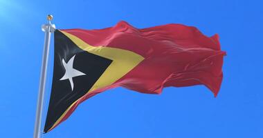 Flag of East Timor waving at wind with blue sky in slow, loop video