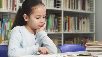 Little girl lost in a book, dreaming in a cozy library video